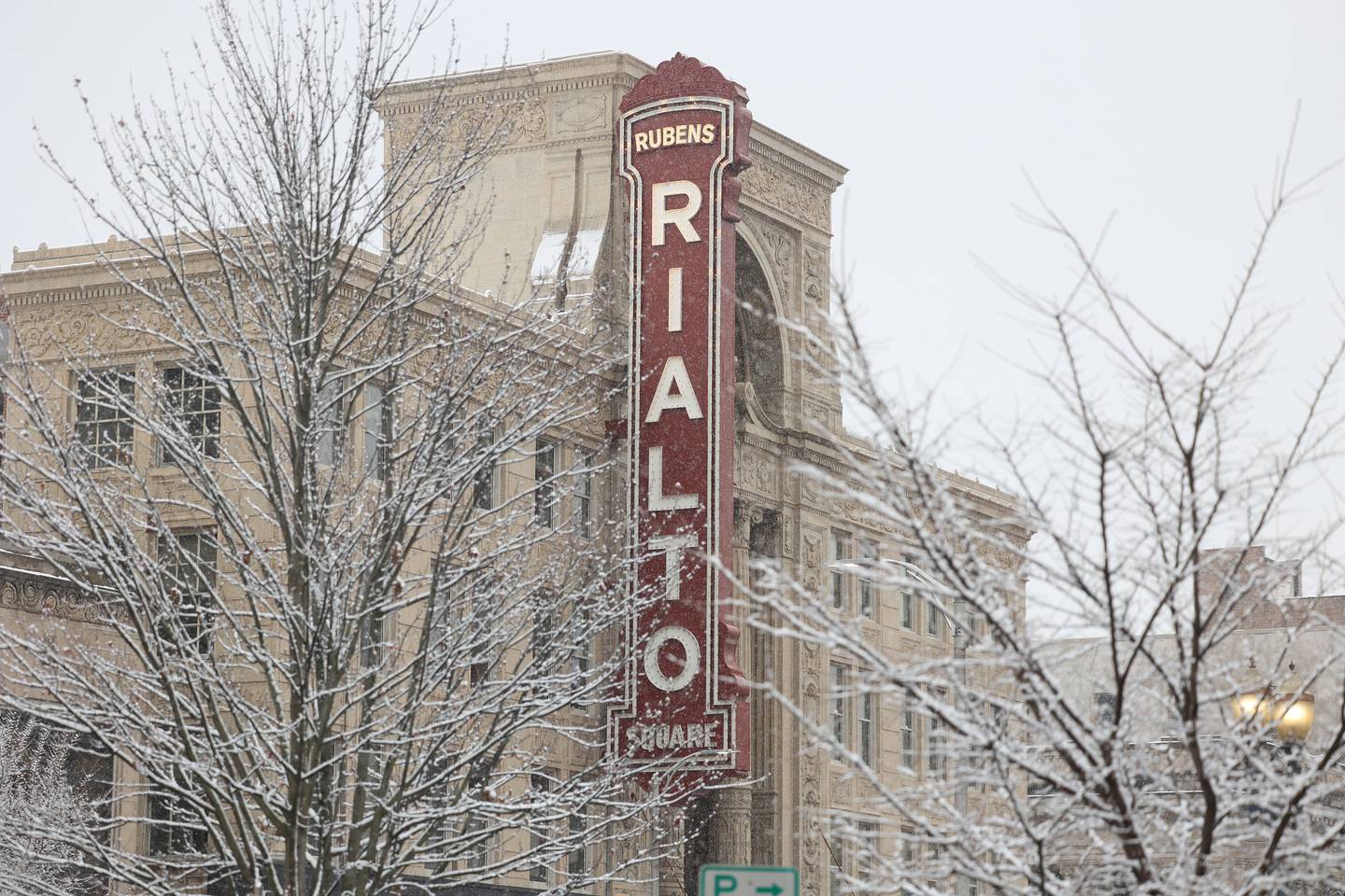 The Rialto sign is visible through several snow dusted trees in downtown Joliet on Sunday, Nov. 26, 2023.